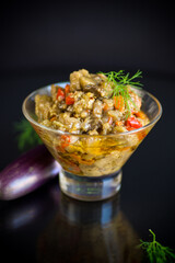 cooked summer eggplant caviar with vegetables in a bowl on black background