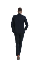 Rear view of cool businessman walking with hands in pockets