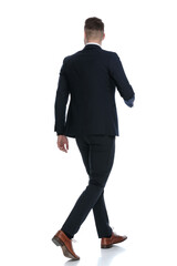 Side rear view of confident wearing suit and stepping