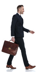 Side view of smiling businessman holding briefcase while stepping