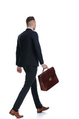 Side rear view of businessman holding briefcase and walking