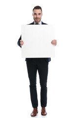 Positive businessman smiling and holding blank billboard