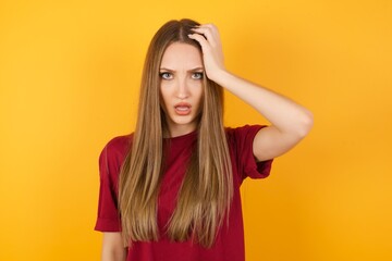 Embarrassed Beautiful Young beautiful caucasian girl wearing red t-shirt over isolated yellow background, with shocked expression, expresses great amazement, Puzzled woman poses indoor