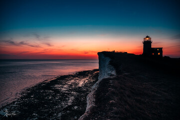 Sunset on edge of cliffs with lighthouse in the back and ocean - sea on horizon © The Nyusz Pusz brand