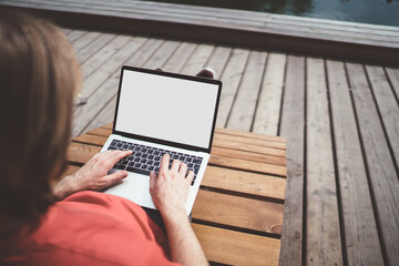 Man typing on laptop in street