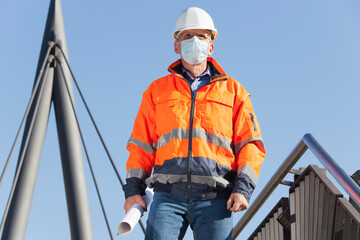 Architect or engineer with face mask and protective clothing walking downstairs