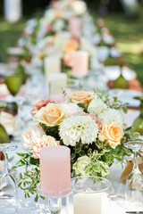 long dinner tables with white cloth, served with porcelains. Georgeous wedding table decorated with flowers and candles