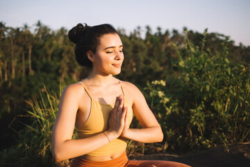 Happy young woman meditating in green grass