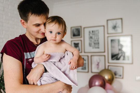 Father hold his baby in the towel after bathing. Dad and her little girl after bath in room.