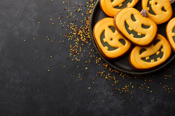 Halloween gingerbread biscuits on black background. Funny pumpkin faces.