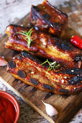 Appetizing grilled pork ribs on a wooden board. Cooking BBQ ribs. Selective focus. Macro.