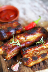 Appetizing grilled pork ribs on a wooden board. Cooking BBQ ribs. Selective focus. Macro.