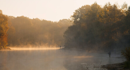 Obraz na płótnie Canvas Men fishing in river with fly rod during summer morning. Beautiful fog.