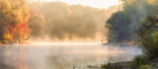 Fototapeta na wymiar Men fishing in river with fly rod during summer morning. Beautiful fog.
