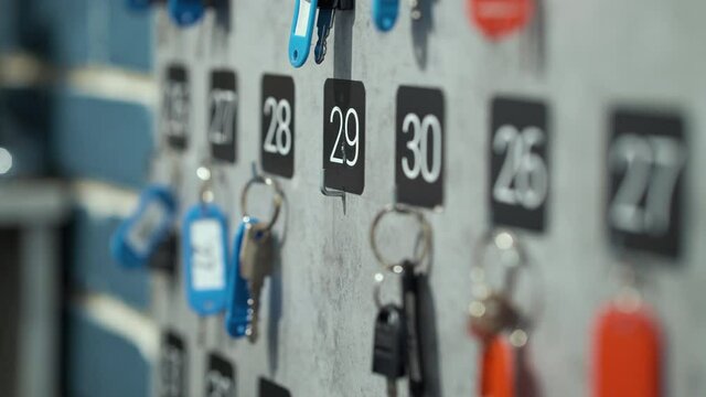Female hand taking locker key from stand with rows of keys. Partial view of receptionist at work. Concept of hotel