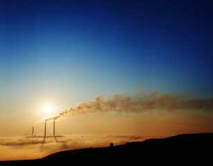 Beautiful scenery of thermal power station with blue sky on background. Chimneys releasing huge amount of smoke into atmosphere. Concept of environmental pollution, ecology and energy generation.
