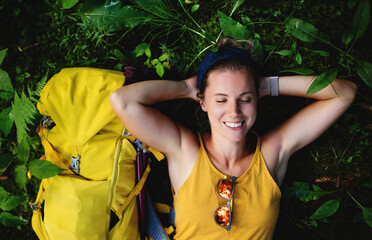 Top view of woman hiker lying on the ground outdoors in forest, resting.