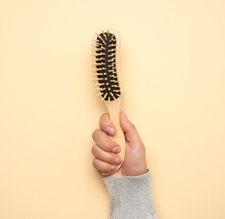 female hand holding a wooden comb