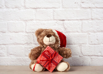 teddy bear in santa claus hat and box tied with red ribbon