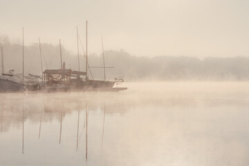 Fototapeta na wymiar Early morning sunrise, boating on the lake in a huge fog