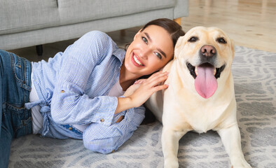 Young happy lady with dog lying on floor