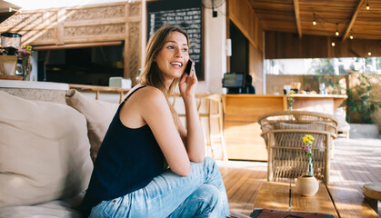 Positive lady talking on mobile phone and smiling in cafe