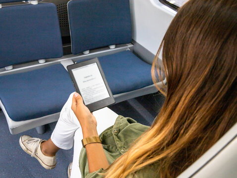 Unrecognizable woman reading e book in train