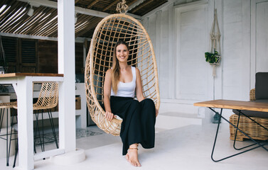 Smiling young female sitting on hanging chair