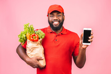 Delivery Concept - Handsome African American delivery man carrying package box of grocery food from store. Isolated on pink studio Background. Copy Space