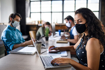 Business people with face masks indoors in office, back to work after coronavirus lockdown.