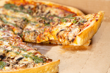Pizza closeup with mushroom, chicken,  pesto, cheese and tomato. One slice is flying out.
