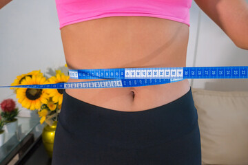The female body with a tape measure. Concept of diet. The woman is measuring the waist