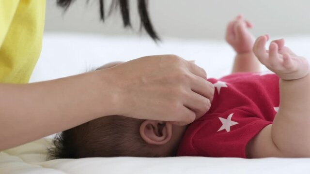 Asian mother takecare her cute baby sleeping and kissing on bed at home.