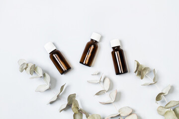 Botellas de aceite esencial de eucalipto junto a ramas de árbol de eucalipto con hojas sobre un...