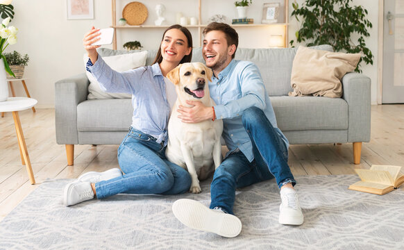 Young couple taking selfportrait with dog at home