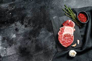Osso Buco meat. Raw cross cut veal shank and seasonings for cooking Osso Buco. Black background. Top view. Copy space