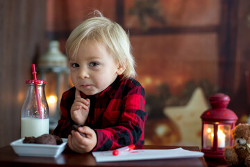 Sweet blonde toddler boy, writing letter to Santa, wishing present for the holidays