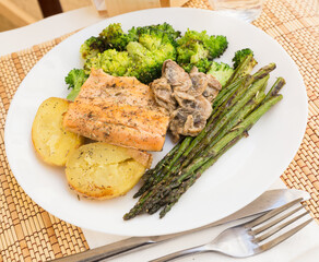delicious dish of fried river trout fillet with garnish of broccoli, asparagus sprouts, baked potatoes and mushroom sauce