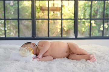 Babies on a white prom bed are sucking milk in a bottle. © subinpumsom