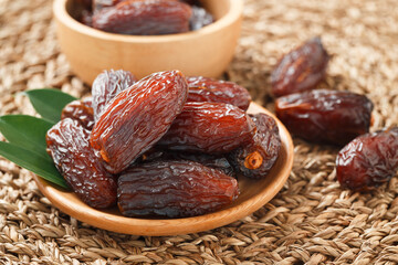 Date fruit in wood bowl on Wicker placemat, Dried date palm fruits top view