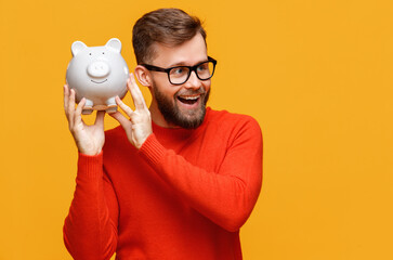 Excited male shaking piggy bank.