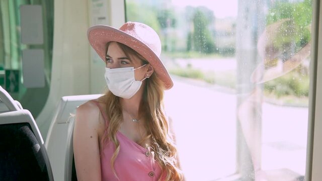 Female traveler riding train in Europe wearing a face mask and a hat. Travel during coronavirus pandemic outbreak. Tourist girl visiting Spain. Stylish woman traveling by local public  transportation