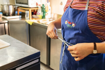 close up of a girl in an industrial kitchen of a mountain shelter wearing a blue apron