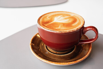 Morning coffee in a ceramic cup with foam on a saucer. Coffee break in a cafe. Aroma fresh cappuccino. Coffee mug on the table.