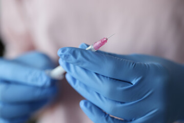 Doctor in rubber gloves holds syringe with medicine closeup. Vaccination against coronavirus infection concept.