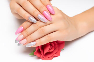 Shiny manicure on sharp long nails with a red rose in the palms. Gel manicure. Pink silver French manicure with crystals.