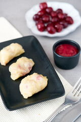 Homemade traditional Russian Ukrainian dumplings vareniki with sour cherry on a black plate vertical view			
