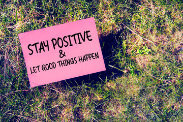 Stay positive and good things happen message written on paper on grass background. Inspirational quote for motivation, happiness or success in relationship or life.