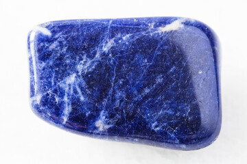 closeup of sample of natural mineral from geological collection - tumbled Sodalite rock on white...