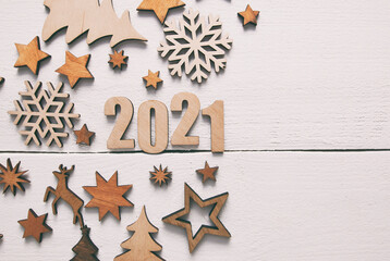 The beautiful christmas background with a lot of small wooden decorations and wooden numbers 2021 on the wooden desk.